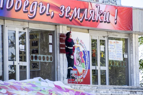 The worker is carrying out repairs at the entrance to the center of culture and leisure of the Oktyabrsky settlement — стоковое фото