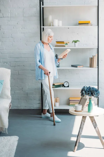 Side View Grey Hair Woman Walking Stick Book Standing Bookshelf — стоковое фото