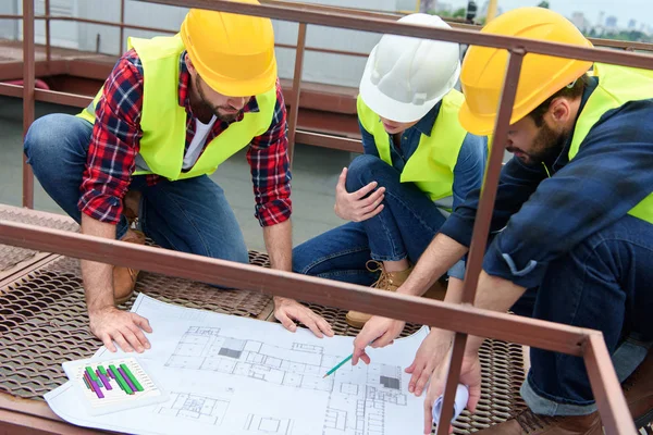 Three Architects Hardhats Working Blueprints Roof — стоковое фото