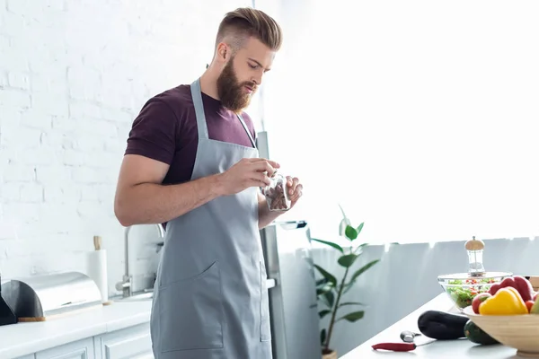 Handsome Bearded Man Apron Holding Container Cinnamon Sticks While Cooking — стоковое фото
